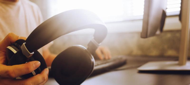 Person holding headphones and listening to music from their computer